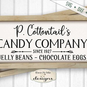 Puede incluir: Un letrero de madera con el texto "P. Cottontail's CANDY COMPANY SINCE 1927 JELLY BEANS - CHOCOLATE EGGS" en letras negras sobre fondo blanco.
