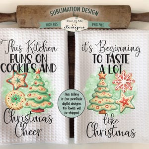 Op de afbeelding: Twee witte keukenhanddoeken met wafelweefsel en kerstthema's. E&eacute;n handdoek leest "This Kitchen Runs on Cookies and Christmas Cheer" en de andere zegt "It's Beginning to Taste a Lot like Christmas". Elke handdoek heeft een kerstboom en koekjesillustraties.