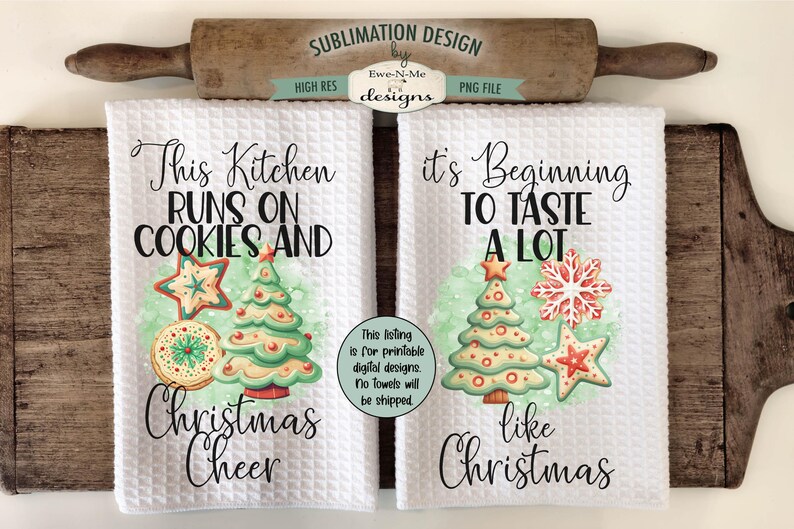 Op de afbeelding: Twee witte keukenhanddoeken met wafelweefsel en kerstthema's. E&eacute;n handdoek leest "This Kitchen Runs on Cookies and Christmas Cheer" en de andere zegt "It's Beginning to Taste a Lot like Christmas". Elke handdoek heeft een kerstboom en koekjesillustraties.