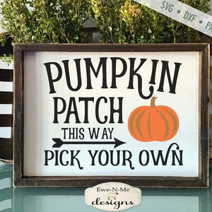 May include: A wooden sign with the text "Pumpkin Patch This Way Pick Your Own" in black lettering. An orange pumpkin with a green stem is to the right of the text. The sign is framed in dark brown wood.