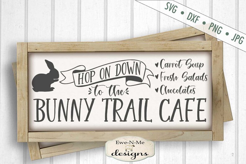 Puede incluir: Un letrero de madera con el texto "Hop on down to the Bunny Trail Cafe" y un conejo de dibujos animados. El letrero tambi&eacute;n enumera los art&iacute;culos del men&uacute;: Sopa de zanahoria, ensaladas frescas y chocolates.