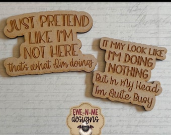 May include: Wooden laser-cut magnet designs with humorous quotes. One magnet reads "Just pretend like I'm not here, that's what I'm doing." The other says "It may look like I'm doing nothing, but in my head I'm quite busy."