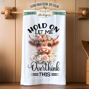 May include: A white kitchen towel featuring a brown and white Highland cow wearing a pink flower crown. The text "HOLD ON LET ME OVERTHINK THIS" is printed in black on the towel.