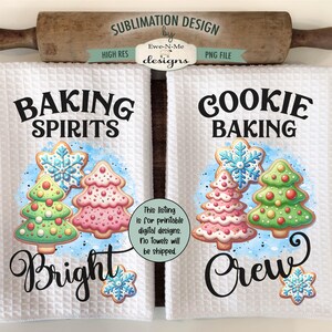Op de afbeelding: Twee witte keukenhanddoeken met wafelweefsel met vakantiethema's. Op de ene handdoek staat "Baking Spirits Bright" en op de andere "Cookie Baking Crew". Elk heeft een kerstboomkoekjesontwerp. Een houten deegroller en snijplank staan op de achtergrond.