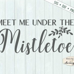 K&ouml;nnte beinhalten: Ein digitales Design auf hellblauem Holzgrund. Der Text lautet "MEET ME UNDER THE Mistletoe" in einer dunkelgrauen Schriftart mit einem Mistelzweig &uuml;ber dem Wort. Das Design enth&auml;lt Dateitypoptionen: SVG, DXF, PNG und JPG.