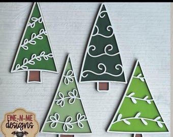 May include: Four laser-cut holiday tree ornaments in varying shades of green with white accents. Each tree has a unique design, including leaf and swirl patterns. The ornaments have brown bases and are set against a light gray background. The text "LASER READY HOLIDAY TREE ORNAMENTS" is at the top.