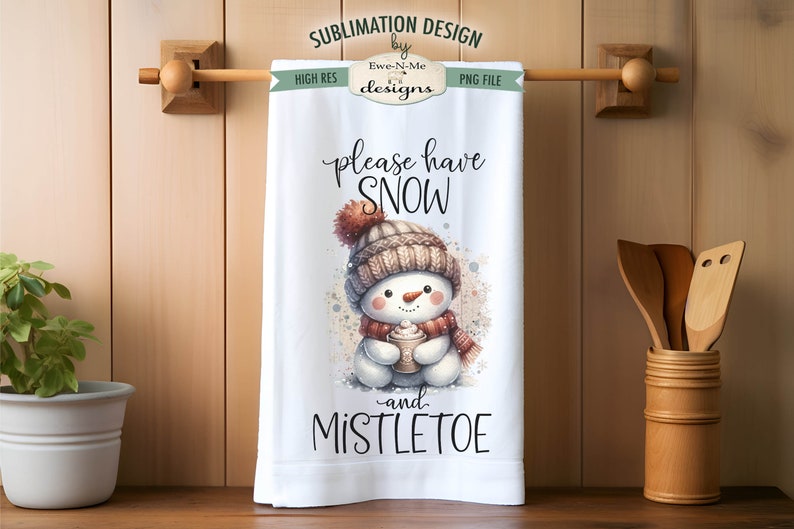 May include: White kitchen towel featuring a charming snowman illustration holding a cup of hot chocolate. The text "please have snow and mistletoe" is printed on the towel.
