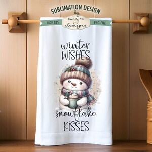 May include: A white kitchen towel with a winter-themed design featuring a snowman holding a cup of hot chocolate. The text on the towel reads "winter wishes snowflake kisses".