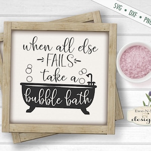 Puede incluir: Un cartel blanco con texto negro que dice "when all else →FAILS→ take a bubble bath". El cartel está enmarcado en un marco de madera marrón claro. Hay un pequeño cuenco de sales de baño rosas y una ramita de lavanda en el fondo.