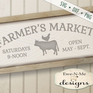以下が含まれることがあります： グレーの「FARMER'S MARKET」の文字が入った長方形の木製フレームの看板。看板には「SATURDAYS 9-NOON」と「OPEN MAY - SEPT.」の文字も含まれています。牛と鶏のシルエットが特徴です。背景は白です。