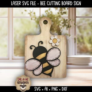 Puede incluir: Tabla de cortar de madera con asa, con un diseño de abeja grande con detalles en negro, amarillo y rosa, y una pequeña margarita. El texto "LASER SVG FILE - BEE CUTTING BOARD SIGN" está en la parte superior. La tabla tiene un acabado envejecido.