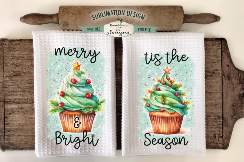 Op de afbeelding: Twee witte keukenhanddoeken met wafelweefsel met kerstboomcupcake-ontwerpen. De ene zegt "Merry & Bright", de andere zegt "Tis the Season". De ontwerpen hebben groene glazuur, rode bessen en een gouden ster.