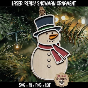 May include: Laser-ready snowman ornament with a black top hat, orange carrot nose, and a red scarf. The wooden ornament has a light brown body and is hanging from a twine loop. The text "LASER-READY SNOWMAN ORNAMENT" is at the top.
