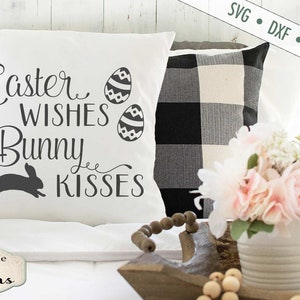 Puede incluir: Almohada blanca con el texto "Easter Wishes Bunny Kisses" en fuente de letra cursiva negra. Dos huevos de Pascua con patrones en blanco y negro est&aacute;n por encima del texto. Una silueta de conejo negro est&aacute; por debajo del texto. La almohada est&aacute; sobre una cama blanca con una almohada a cuadros en blanco y negro detr&aacute;s.
