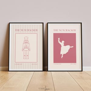 May include: Two framed art prints featuring designs from The Nutcracker ballet. One print shows a nutcracker soldier, the other a ballerina. Both prints have a pink and cream color scheme and the text "The Nutcracker" and "Since 1892".