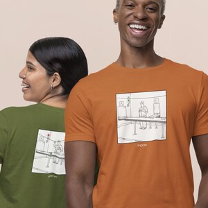 May include: Two people wearing t-shirts with a black and white illustration of a bar scene. The person on the left is wearing a green t-shirt and yellow pants. The person on the right is wearing an orange t-shirt and beige pants.