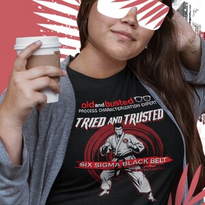 May include: A black t-shirt with a white graphic of a person in a karate pose. The text on the shirt reads "old and busted PROCESS CHARACTERIZATION EXPERT TRIED AND TRUSTED SIX SIGMA BLACK BELT".