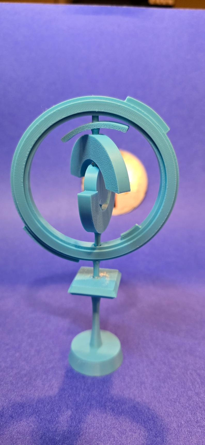 May include: A blue 3D printed sculpture with a circular design and a base. The sculpture is made of multiple interlocking pieces.