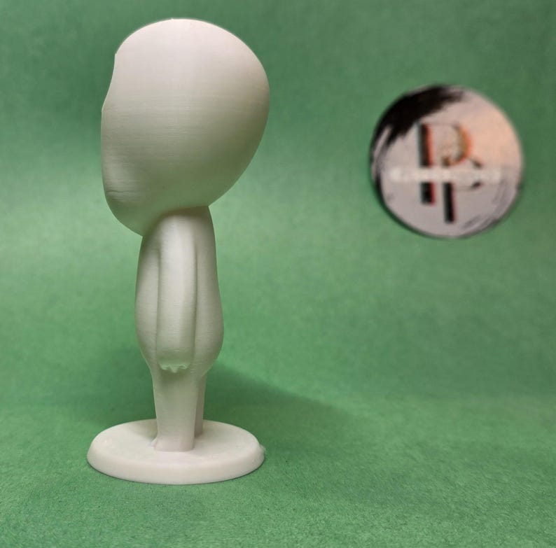 May include: A white 3D printed figurine of a person with a large head and no facial features. The figurine is standing on a round base.