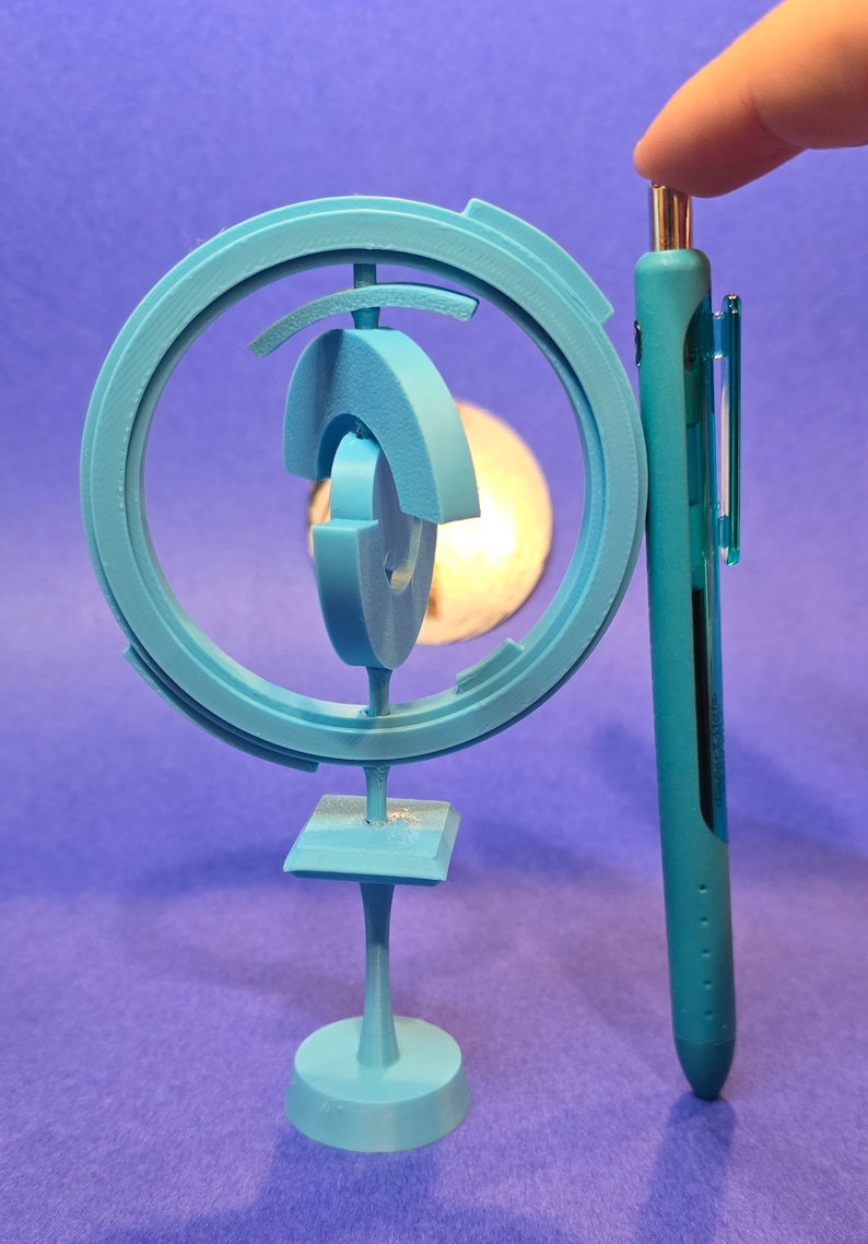 May include: A light blue 3D printed sculpture with a circular design and a base. The sculpture is about the size of a pen.