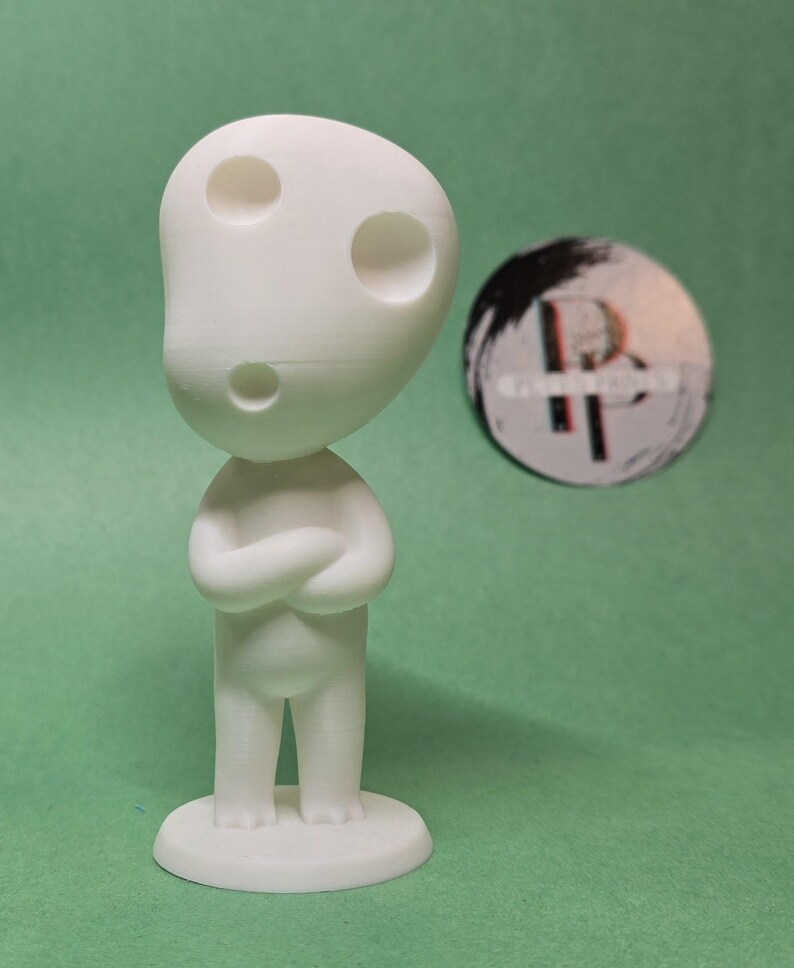 May include: White figurine of a character with three holes in its head, standing on a round base. The character has its arms crossed and is looking straight ahead.