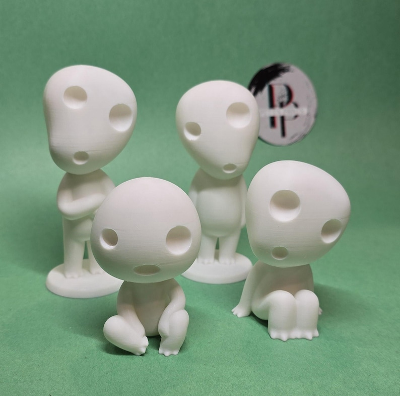 May include: Four white figurines of a character from the movie 'My Neighbor Totoro'. The figurines are all different poses, with one sitting, one standing with arms crossed, and two standing with arms at their sides.