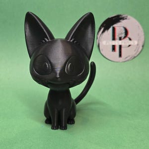 May include: A black cat figurine with large eyes and a small smile. The figurine is made of a smooth, matte black plastic.