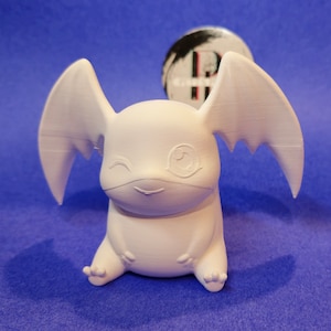 May include: White 3D printed figurine of a cartoon character with large ears and wings. The character has a closed eye and a smiling mouth.