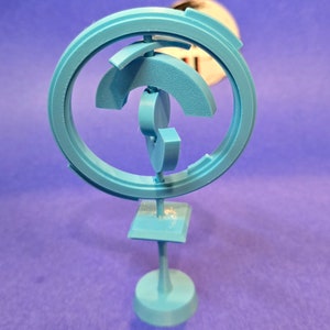 May include: A light blue 3D printed sculpture with a circular design and a square base. The sculpture is made of multiple interlocking pieces.