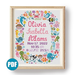 May include: A cross-stitch pattern featuring a colorful underwater scene with sea creatures, bubbles, and seaweed. The pattern includes the name "Olivia Isabella Adams", the date "Nov 17, 2022", the time "10:35 am", and the measurements "8 lbs 7 oz 21.5 in".
