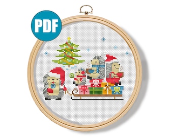 Peut inclure: Une broderie au point de croix dans un cercle en bois représente une scène de Noël avec des hérissons portant des bonnets de Père Noël, tirant un traîneau rempli de cadeaux. Un sapin de Noël et des flocons de neige sont également inclus. L'icône PDF est en haut à gauche.