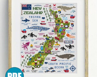Peut inclure: Un modèle de point de croix encadré représentant une carte de la Nouvelle-Zélande avec les îles du Nord et du Sud, le drapeau national et diverses icônes régionales incluant la faune marine, des monuments et des noms de lieux comme Wellington.