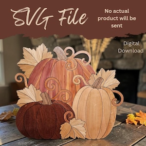 May include: A digital download SVG file featuring a layered illustration of three pumpkins in varying shades of brown and tan wood grain, accented with decorative swirling vines and maple leaves. Text reads SVG File, No actual product will be sent.