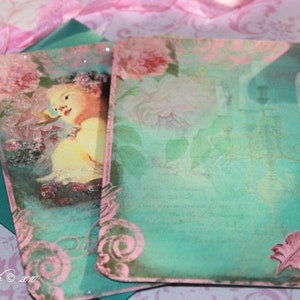 May include: Two teal green cards with pink floral designs and a pink feather on one card. The cards have a vintage aesthetic and are perfect for scrapbooking or crafting.