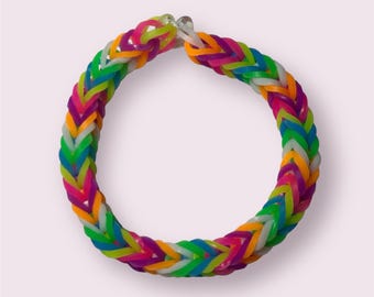May include: A colorful rubber band bracelet in a fishtail braid pattern. The bracelet features a vibrant mix of neon green, orange, pink, purple, blue, and white bands. The bracelet is a fun accessory for kids and adults.