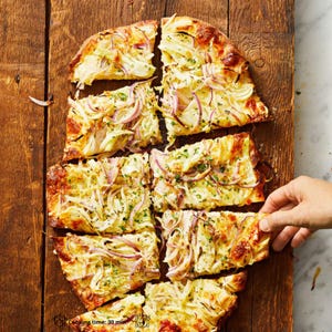Puede incluir: Una pizza rectangular cortada en rodajas, cubierta con cebollas, hierbas y rodajas de cebolla roja. La pizza está sobre una tabla de cortar de madera. El texto "Cooking time: 30 min" es visible.