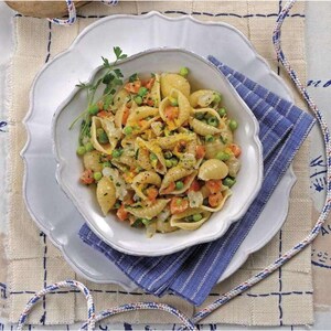 Puede incluir: Un cuenco blanco con borde festoneado lleno de conchas de pasta, guisantes y zanahorias en dados, adornado con perejil. El cuenco está sobre un plato blanco, sobre una servilleta azul a rayas. Cuerdas decorativas acentúan la escena.