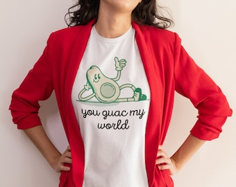 May include: A white t-shirt with a green avocado cartoon character wearing a smile and giving a thumbs up. The text "you guac my world" is printed below the avocado.