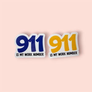 May include: Two stickers with the number 911 in blue and yellow, with the text "IS MY WORK NUMBER" below each. The stickers have a white border and are set against a light pink background.