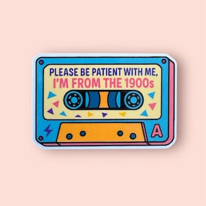 May include: A sticker in the shape of a cassette tape with a retro design. The sticker is blue, orange, and yellow with the text "PLEASE BE PATIENT WITH ME, I'M FROM THE 1900s". The cassette tape has a white border and a pink background.
