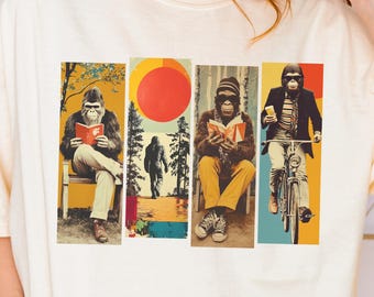 May include: An ivory t-shirt featuring a graphic print of four vertical panels. The panels depict a gorilla reading on a bench, a silhouette of a creature in a forest with a red sun, a gorilla reading in a chair, and a gorilla riding a bicycle.