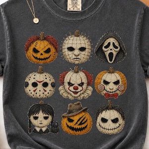 May include: A charcoal gray short-sleeve t-shirt featuring a graphic print of nine distinct horror-themed characters styled as pumpkins. The design includes iconic faces from various films, arranged in a grid pattern on the front of the garment.