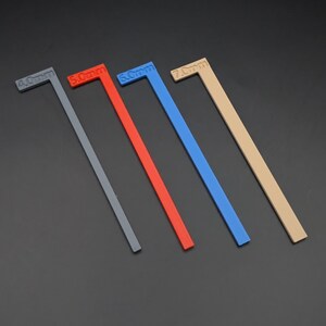 May include: Four L-shaped plastic measuring tools in grey, red, blue, and tan, each labelled with a millimeter measurement: 4.0mm, 5.0mm, 6.0mm, and 7.0mm. The tools are arranged diagonally against a dark background.
