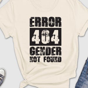 May include: A white t-shirt with black text that reads "ERROR 404 GENDER NOT FOUND".