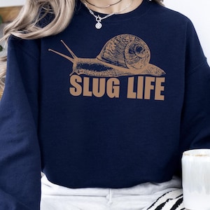 May include: A navy blue sweatshirt with a brown snail graphic and the text "SLUG LIFE" printed on the front.
