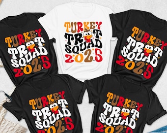 May include: A collection of black and white t-shirts with the text "TURKEY TROT SQUAD 2025" in a retro font, featuring a cartoon turkey. The shirts are short-sleeved and have a crew neck. Accessories include a straw hat, sunglasses, and a denim jeans.