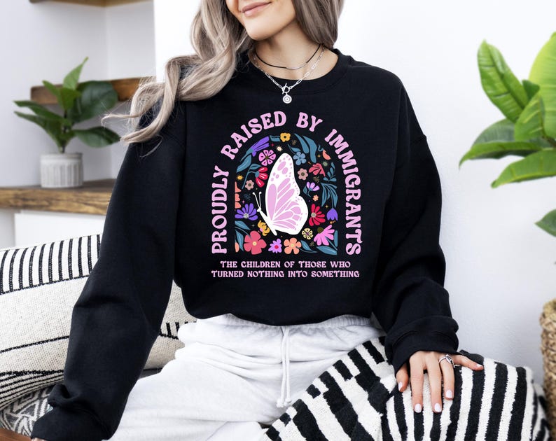 A woman wearing a black sweatshirt with a colorful graphic design and text printed on it.