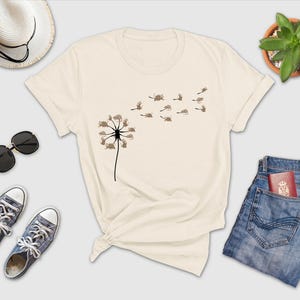 a t - shirt with a dandelion on it next to a pair of