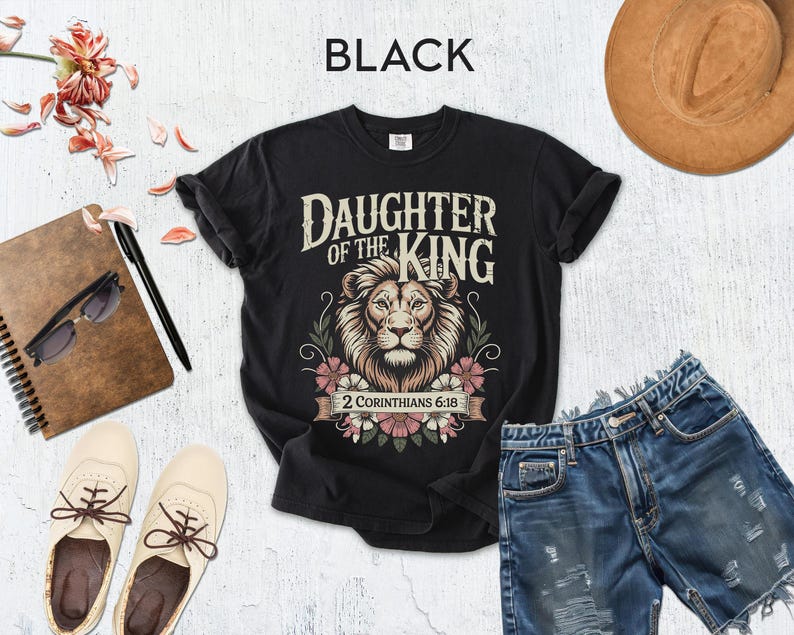 a casual outfit consisting of a black t-shirt with a lion graphic, distressed denim shorts, a brown hat, sunglasses, a notebook, and a pair of white sneakers.