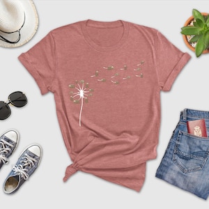 a t - shirt with a dandelion on it next to a pair of